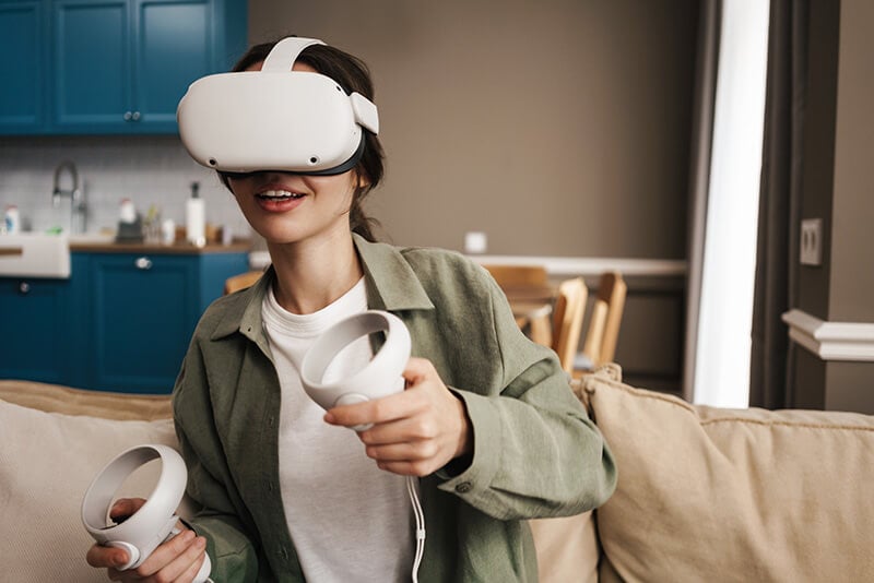 Eine Frau mit einem Virtual Reality Headset und zwei Hand-Controllern.